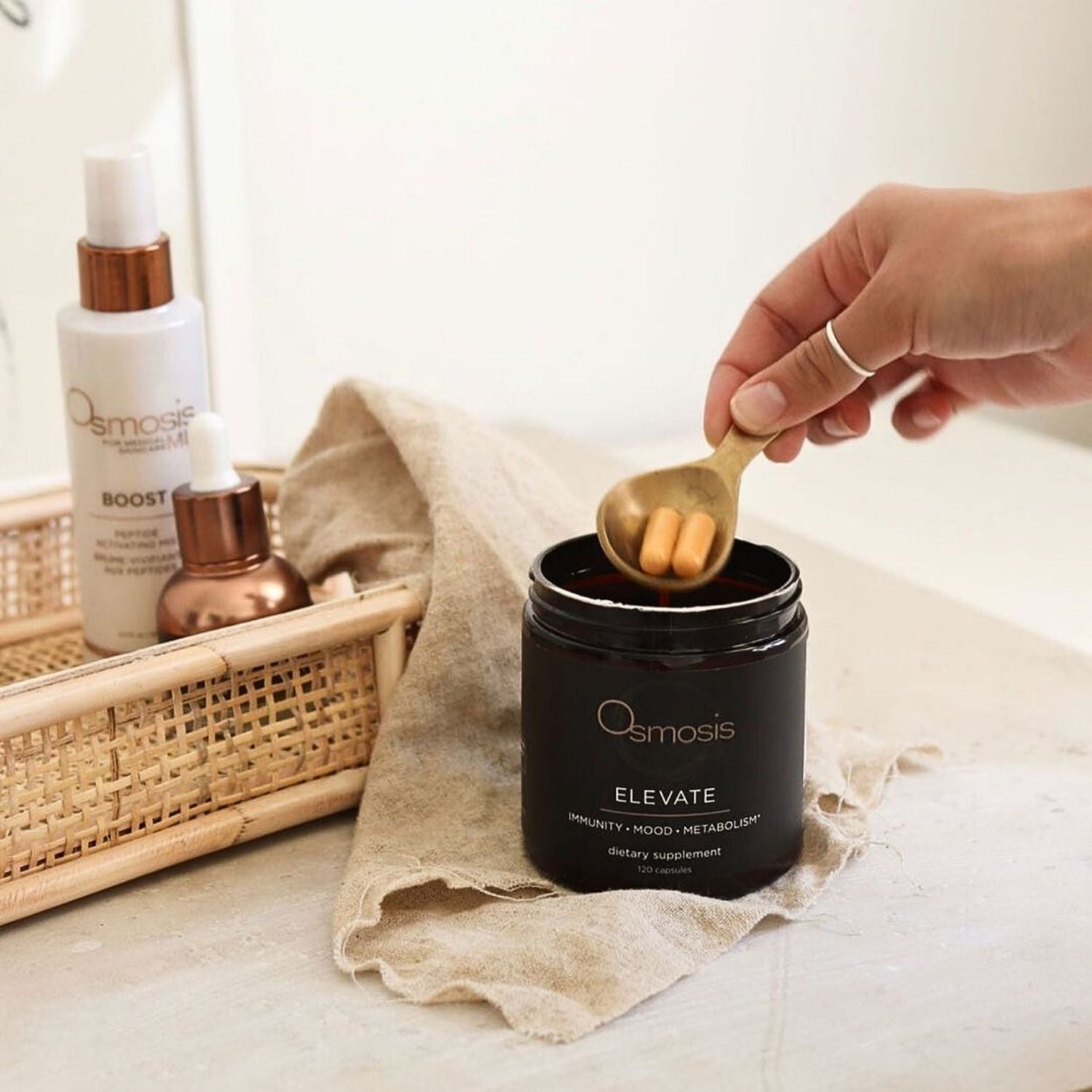 model scooping elevate capsules out of container with other osmosis products nearby