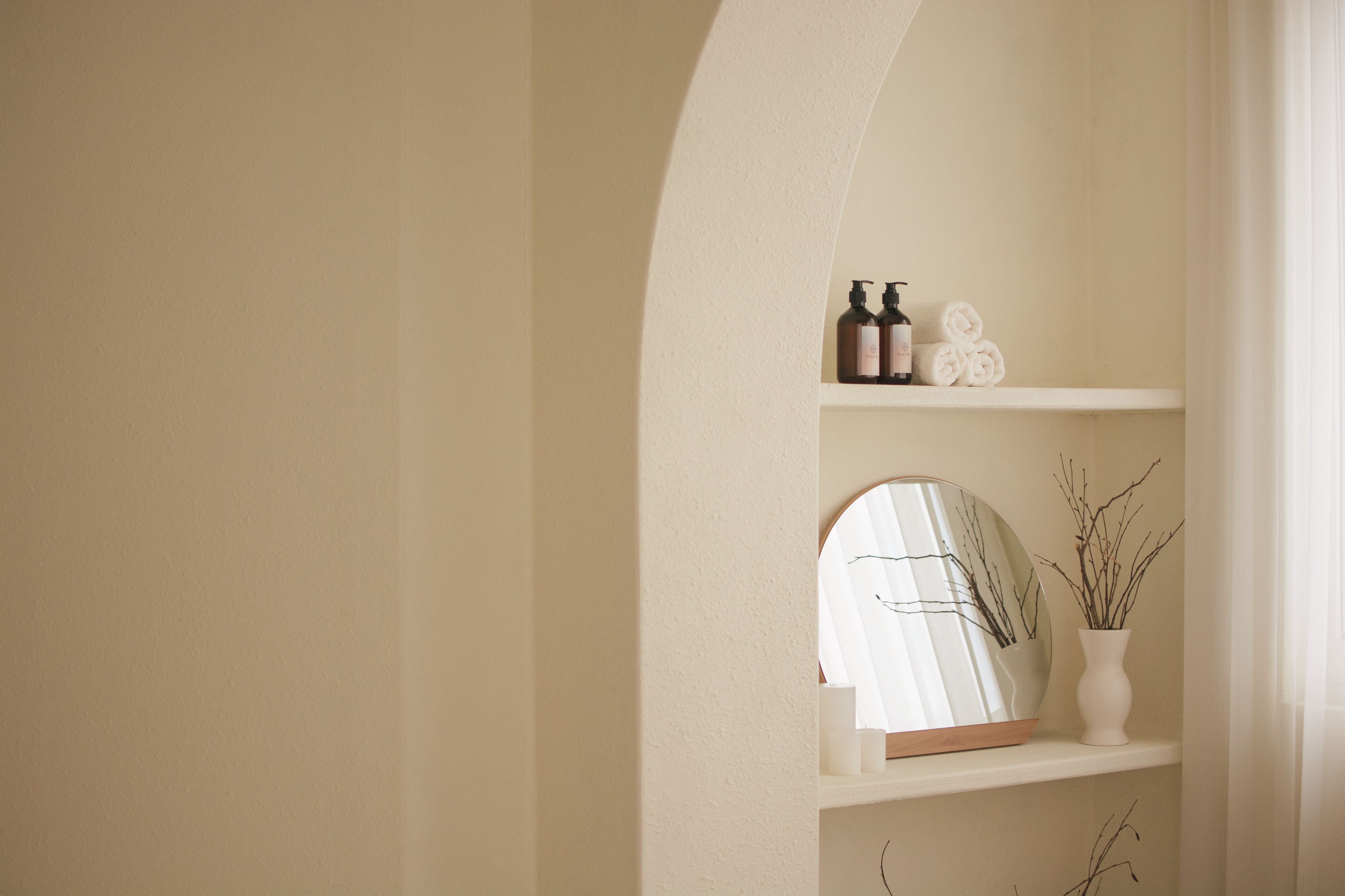 Shelving unit with a mirror and decorative items against a beige wall
