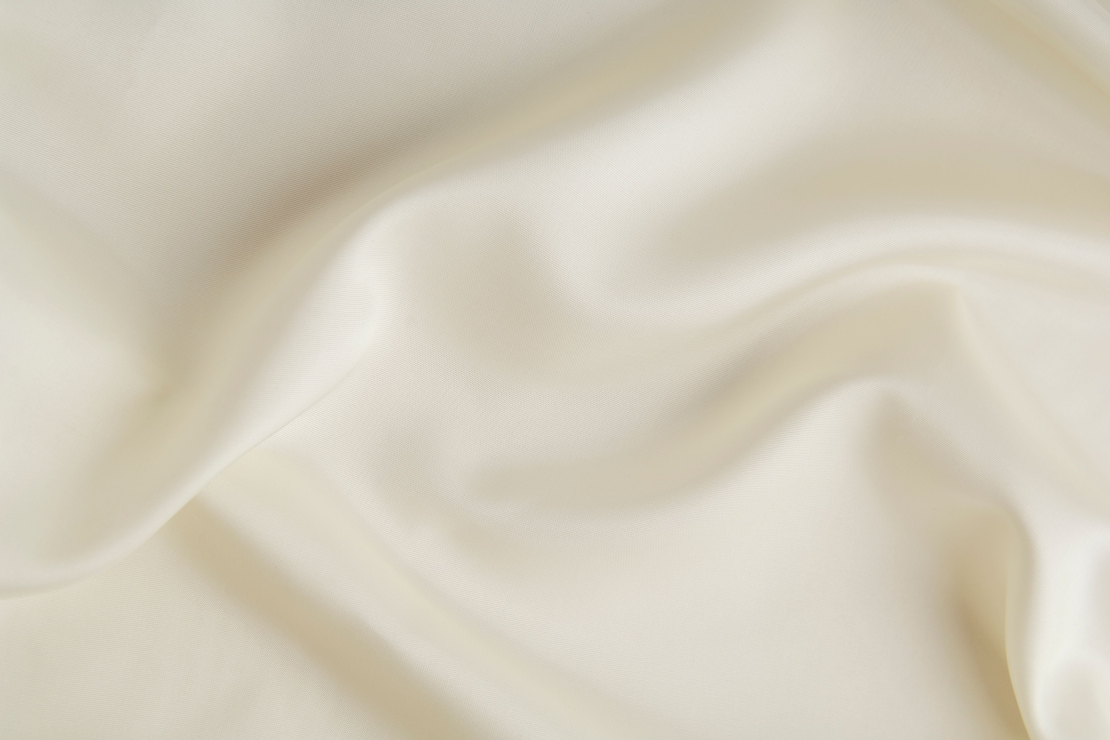 Close-up of smooth, beige fabric with soft folds